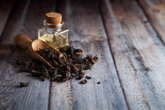 Dry organic Nagarmotha (Cyperus scariosus) roots, in a wooden scoop along with its essential oil.