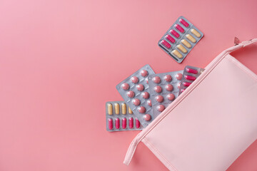 Flat lay composition with pink female toiletry bag blisters on color background