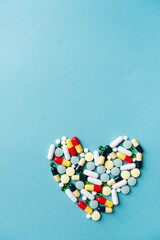 heart shape made of different pills on blue background