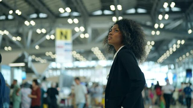 African businesswoman looking flight schedule on timetable and go to check-in and boarding gate in airport terminal. Business people working with travel by airplane transportation on holiday vacation.