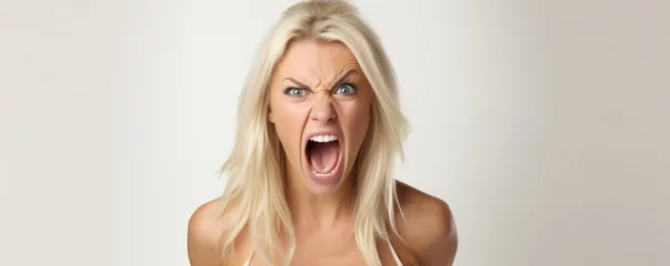 Fotobehang Angry young blonde woman screaming on white background. Anger expression concept. © Daniela