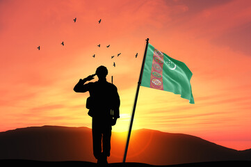 Silhouette of a soldier with the Turkmenistan flag stands against the background of a sunset or sunrise. Concept of national holidays. Commemoration Day.