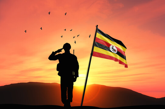 Silhouette of a soldier with the Uganda flag stands against the background of a sunset or sunrise. Concept of national holidays. Commemoration Day.