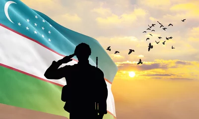 Fotobehang Silhouette of a soldier with the Uzbekistan flag stands against the background of a sunset or sunrise. Concept of national holidays. Commemoration Day. ©  minionionniloy