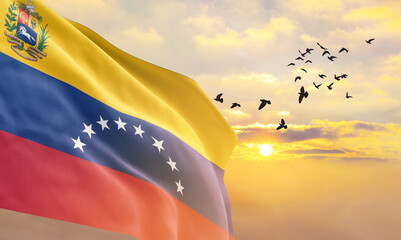 Waving flag of Venezuela against the background of a sunset or sunrise. Venezuela flag for Independence Day. The symbol of the state on wavy fabric.