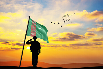 Silhouette of a soldier with the Turkmenistan flag stands against the background of a sunset or...