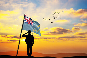 Silhouette of a soldier with the Tuvalu flag stands against the background of a sunset or sunrise....