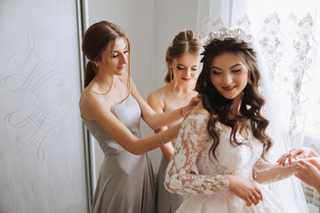 Friends rejoice with the bride in the morning. They take pictures, smile, help the bride fasten her...