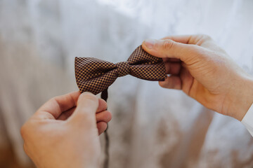 man's tie in hands, close-up photo of hands. The groom is preparing for the ceremony. Last...