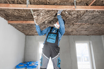 Ceiling insulation. The Worker putting a thermal insulation from glass wool.