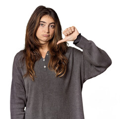 Young Caucasian woman in studio setting showing a dislike gesture, thumbs down. Disagreement...