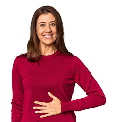 Elegant middle-aged Caucasian woman in studio setting touches tummy, smiles gently, eating and...