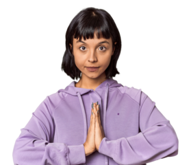 Young Hispanic woman with short black hair in studio praying, showing devotion, religious person looking for divine inspiration.