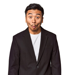 Young Chinese man in business suit in studio shrugs shoulders and open eyes confused.