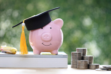 Graduation hat on piggy and stack of coins money on natural green background, Saving money for education concept