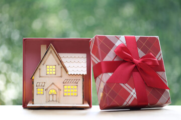 Real estate and Gift new home concept,Model house and gift box with red ribbon for Christmas and...