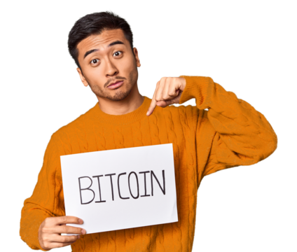 Young Chinese man holding a "bitcoin" sign in studio background