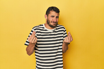 Young Hispanic man on yellow background showing that she has no money.
