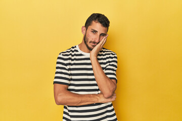 Young Hispanic man on yellow background who is bored, fatigued and need a relax day.