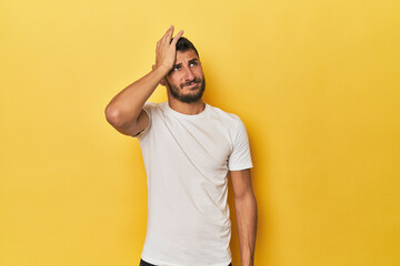 Young Hispanic man on yellow background forgetting something, slapping forehead with palm and closing eyes. - obrazy, fototapety, plakaty