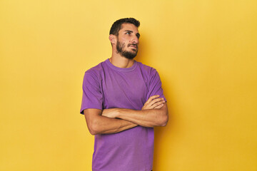 Young Hispanic man on yellow background tired of a repetitive task.