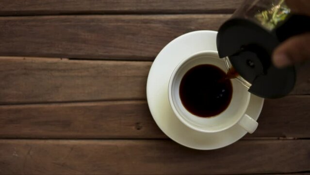 Top view of fresh black coffee poured into empty cup on wooden background, dark coffee drink, health benefits of espresso, americano, breakfast concept
