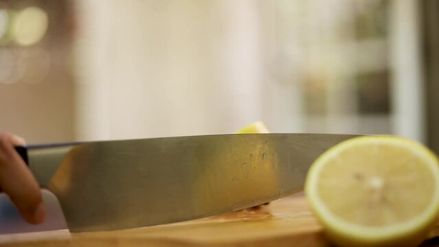 Woman's hand cutting a lemon in half on a cutting board Healthy foods that contain vitamin C
