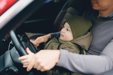 Man father teaches his little son to drive car. Concept love for cars since childhood