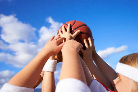 People, hands and basketball in teamwork for sports motivation, unity or community with blue sky background. Group of players holding ball up in air for friendly match or outdoor game in nature