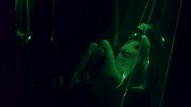 sexy tripper lady moving seductively in dark studio with green laser rays, silhouette in darkness