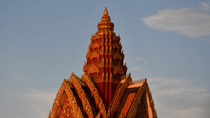 Old orange Buddhist tower of stone at center is scenic historic architecture with blue sky in landscape view