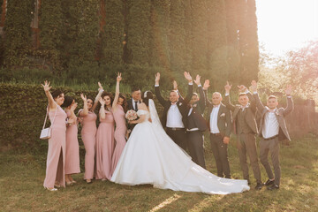 full-length portrait of the newlyweds and their friends at the wedding. The bride and groom with bridesmaids and friends of the groom are having fun and rejoicing at the wedding. - Powered by Adobe