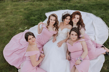 Group portrait of the bride and bridesmaids. Bride in a wedding dress and bridesmaids in pink or powder dresses and holding stylish bouquets on the wedding day.