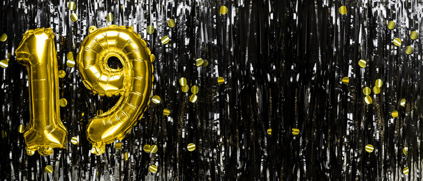 Gold foil balloon number number 19 on a background of black tinsel decoration. Birthday greeting card, inscription nineteen. Anniversary event. Banner.