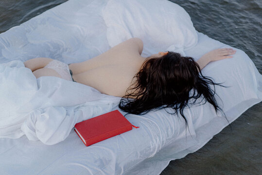 A woman lying on a mattress in the water.