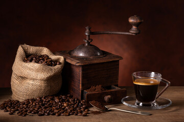 coffee beans in a jute bag, an old grinder and an espresso in a glass cup. - 700973351