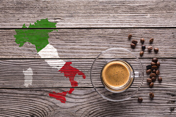 top view glass cup with espresso, some coffee beans and the shape of Italy with the colors of its flag on a gray textured wooden background. - 700973501