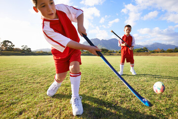 Children, ball and playing hockey on green grass for game, sports or outdoor match together. Team,...