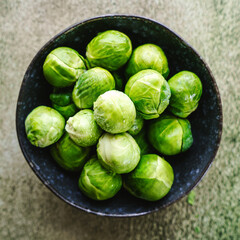 Draufsicht auf rohen Rosenkohl in einer Schüssel auf einem grünen Tisch. Gemüse.