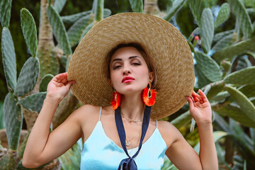 Stylish female model against green cactuses