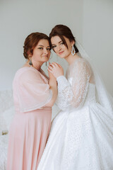 A beautiful and happy mother and her daughter, the bride, are standing next to each other. The best day for parents. Tender moments at the wedding.