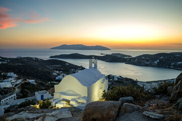 Panoramic view of a small chapel, and the picturesque  illuminated port of Ios in Greece while the...