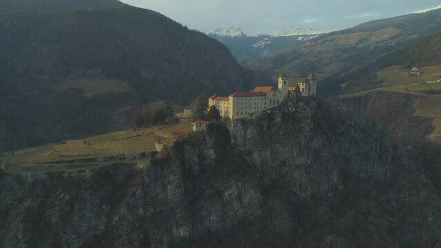 Wide aerial of castle perched on the top of a rocky mountain in the Italian Dolomites