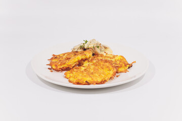 A plate of potato pancakes decorated with basil leaves on the table.