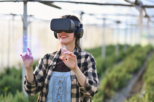 Farmer wearing VR headset for controlling process in greenhouse cultivation. Modern and smart agriculture concept. - Powered by Adobe