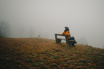 contemplating woman sitting on a bench in the mist