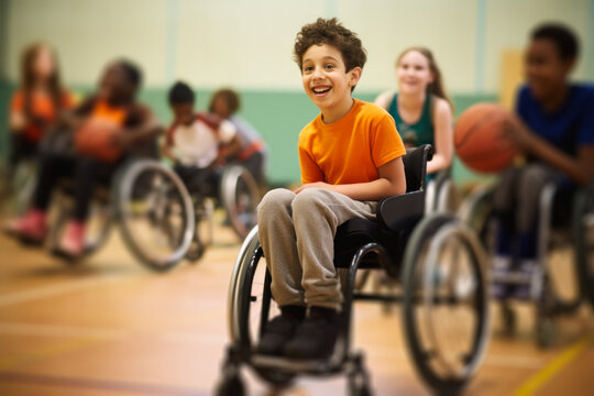 Cheerful Young Boy In Wheelchair Playing Basketball.