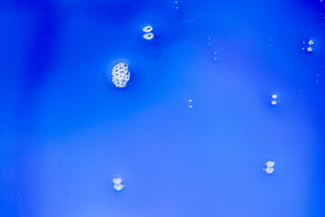 Photograph of water droplets clumping together in groups. The background is blue. Take photos with...