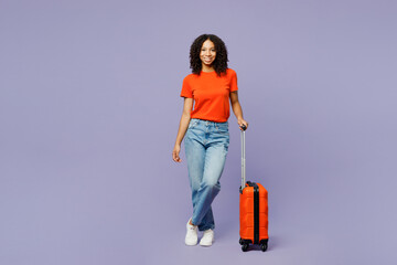 Traveler fun little kid teen girl wear orange t-shirt hold bag isolated on plain pastel purple background studio. Tourist travel abroad in free spare time rest getaway Air flight trip journey concept