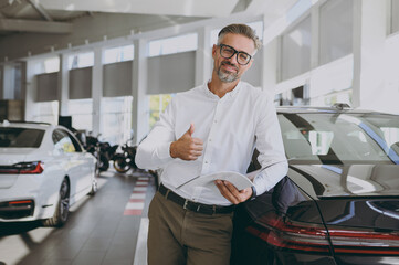 Adult man customer male buyer client in shirt read car papers document agreement show thumb up...